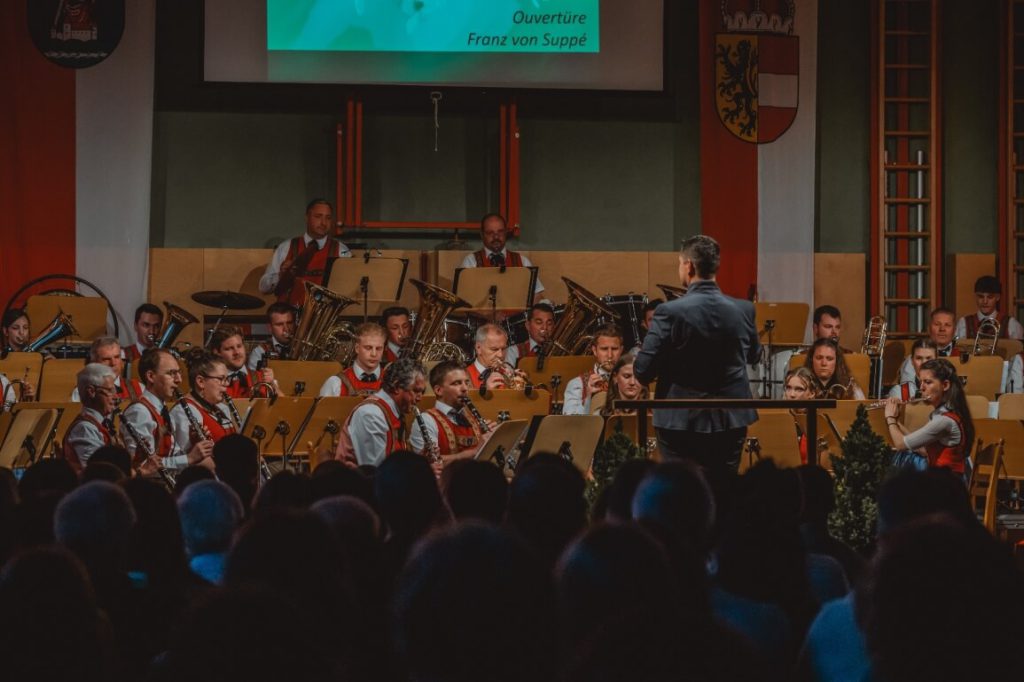 Trachtenmusikkapelle Taxenbach mit Dirigent beim Konzert vor Publikum in traditioneller Blasmusik