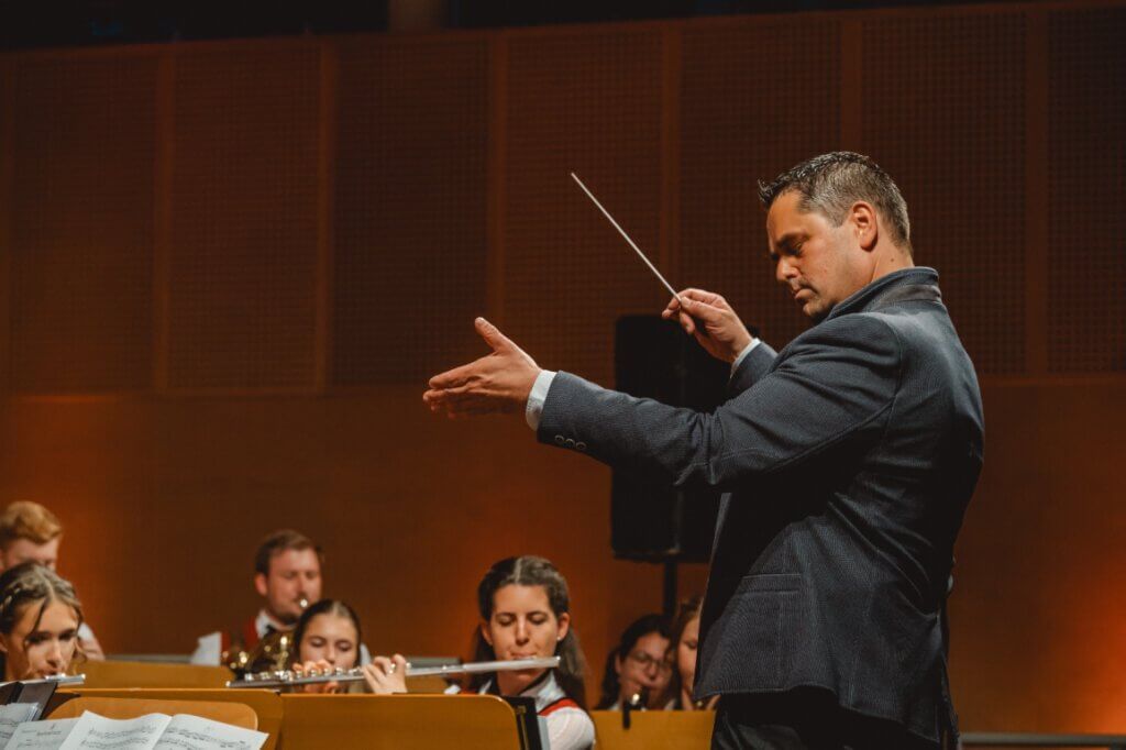 Dirigent leitet konzentriert die Blasmusik der Trachtenmusikkapelle Taxenbach beim Konzert