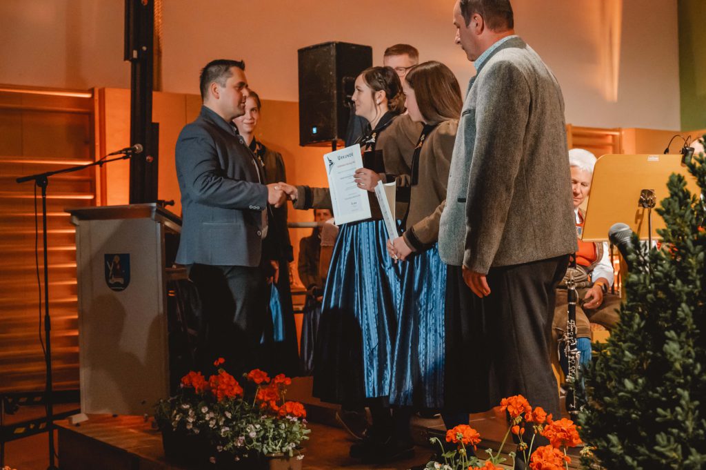 Personen in Tracht bei Urkundenübergabe bei Veranstaltung der Trachtenmusikkapelle Taxenbach