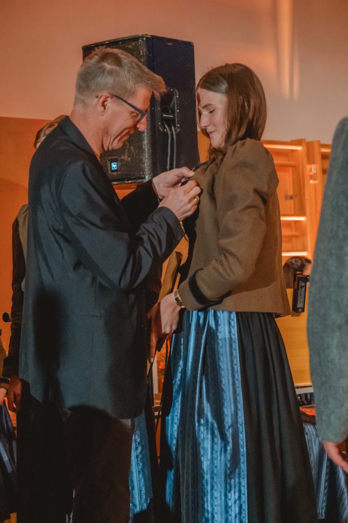 Übergabe einer Anstecknadel bei Trachtenmusikkapelle Taxenbach in traditioneller Blasmusik-Kleidung
