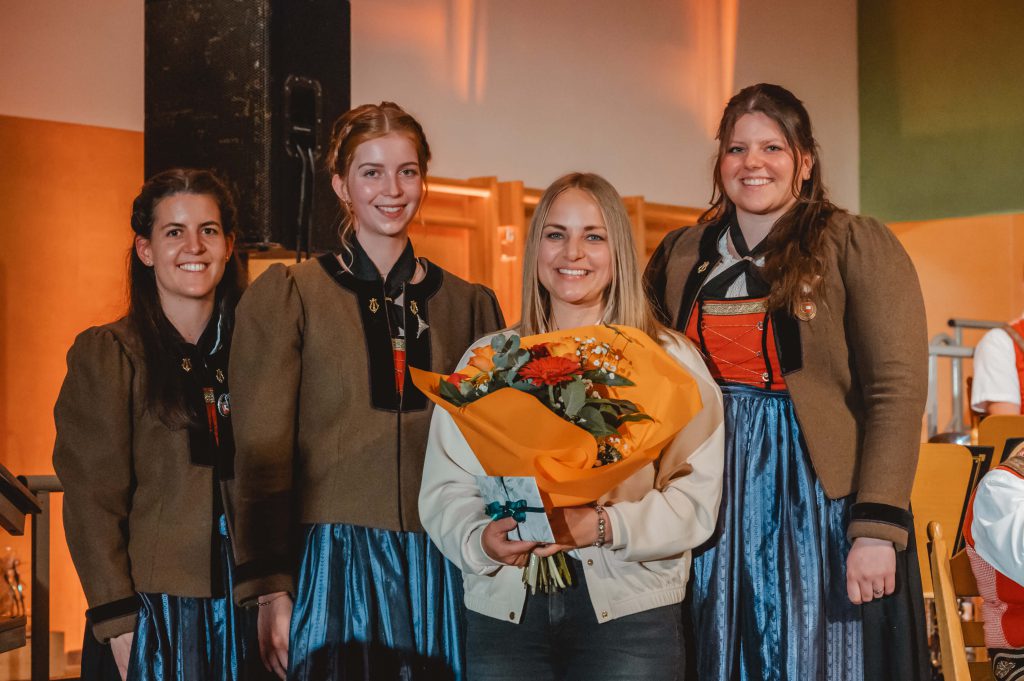 Vier Frauen, drei in Tracht, eine hält Blumenstrauß bei Musikkapelle Taxenbach Veranstaltung