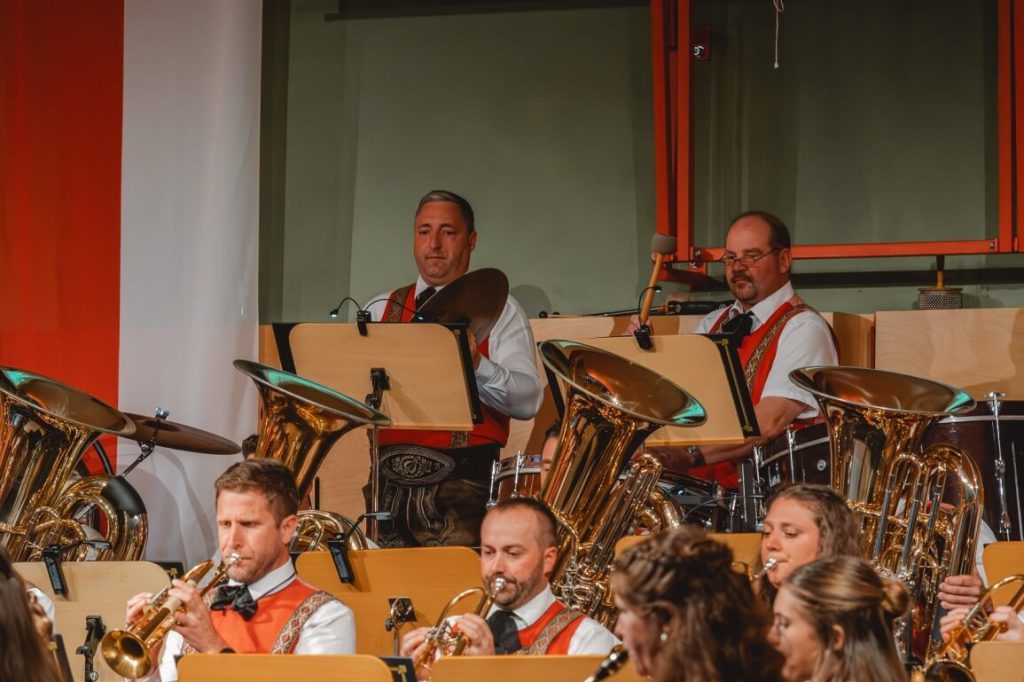 Musiker der Trachtenmusikkapelle Taxenbach spielen Blasinstrumente bei Konzert in Tracht