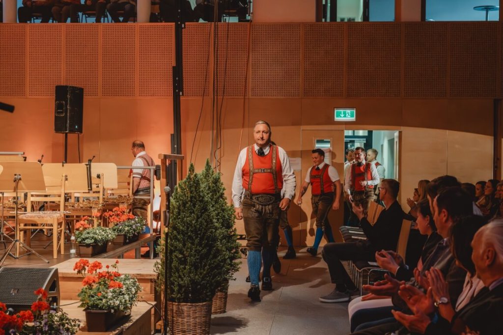 Mitglieder der Trachtenmusikkapelle Taxenbach betreten in traditioneller Blasmusiktracht die Bühne